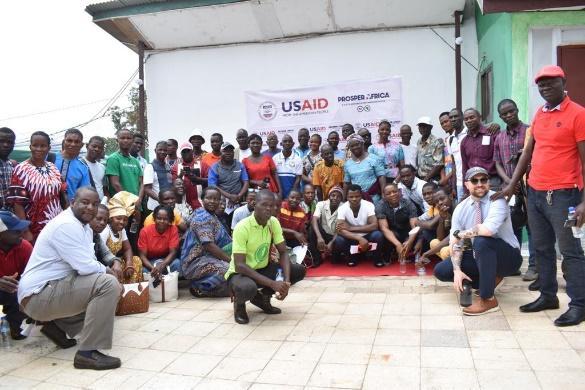 People gather in front of a USAID banner.